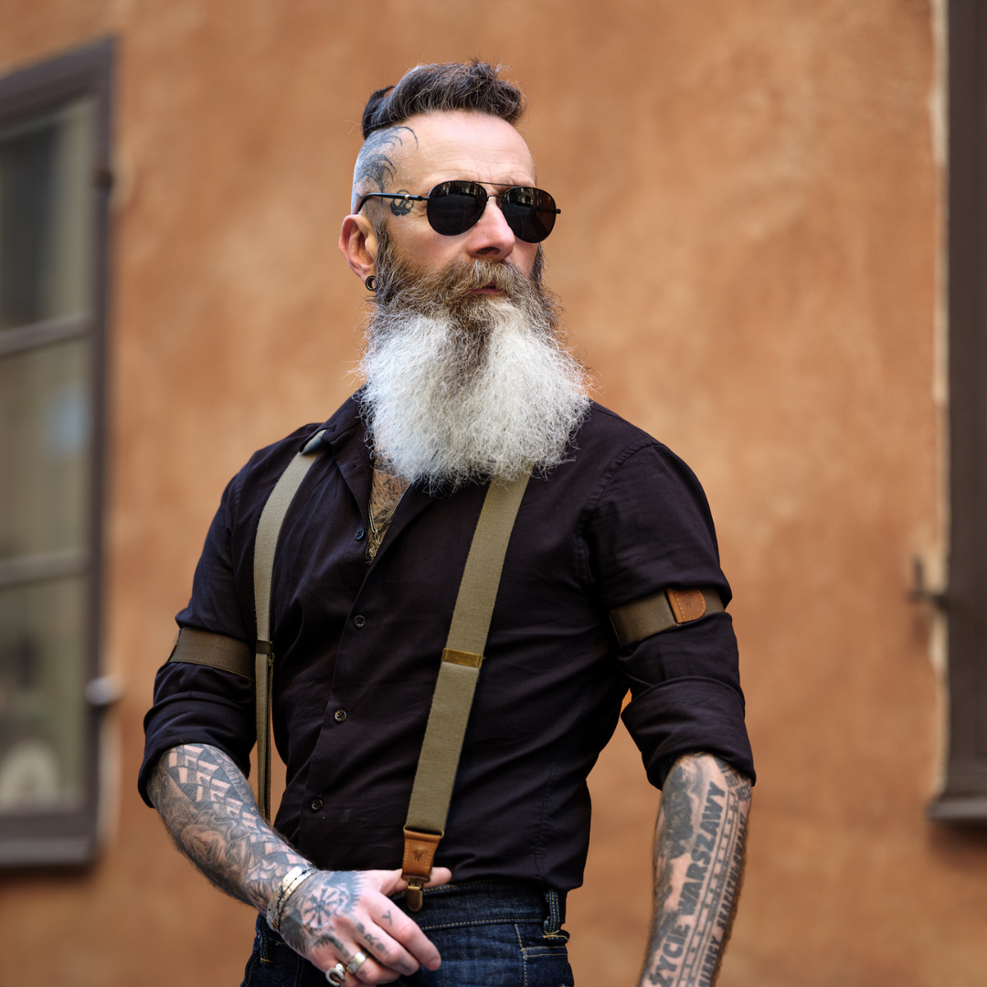 Man wearing Army Green Wiseguy Original Suspenders and Sleeve Garters, a black shirt and aviator sunglasses