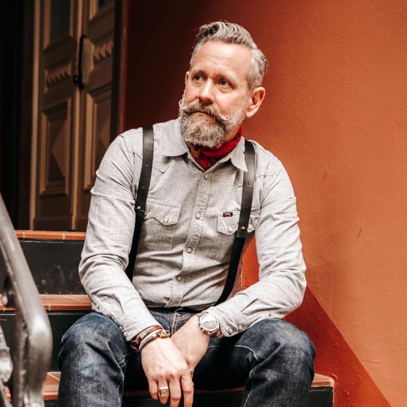 Man wearing black leather Wiseguy Original uspenders with workwear shirt. Her has a mustache and a beard.